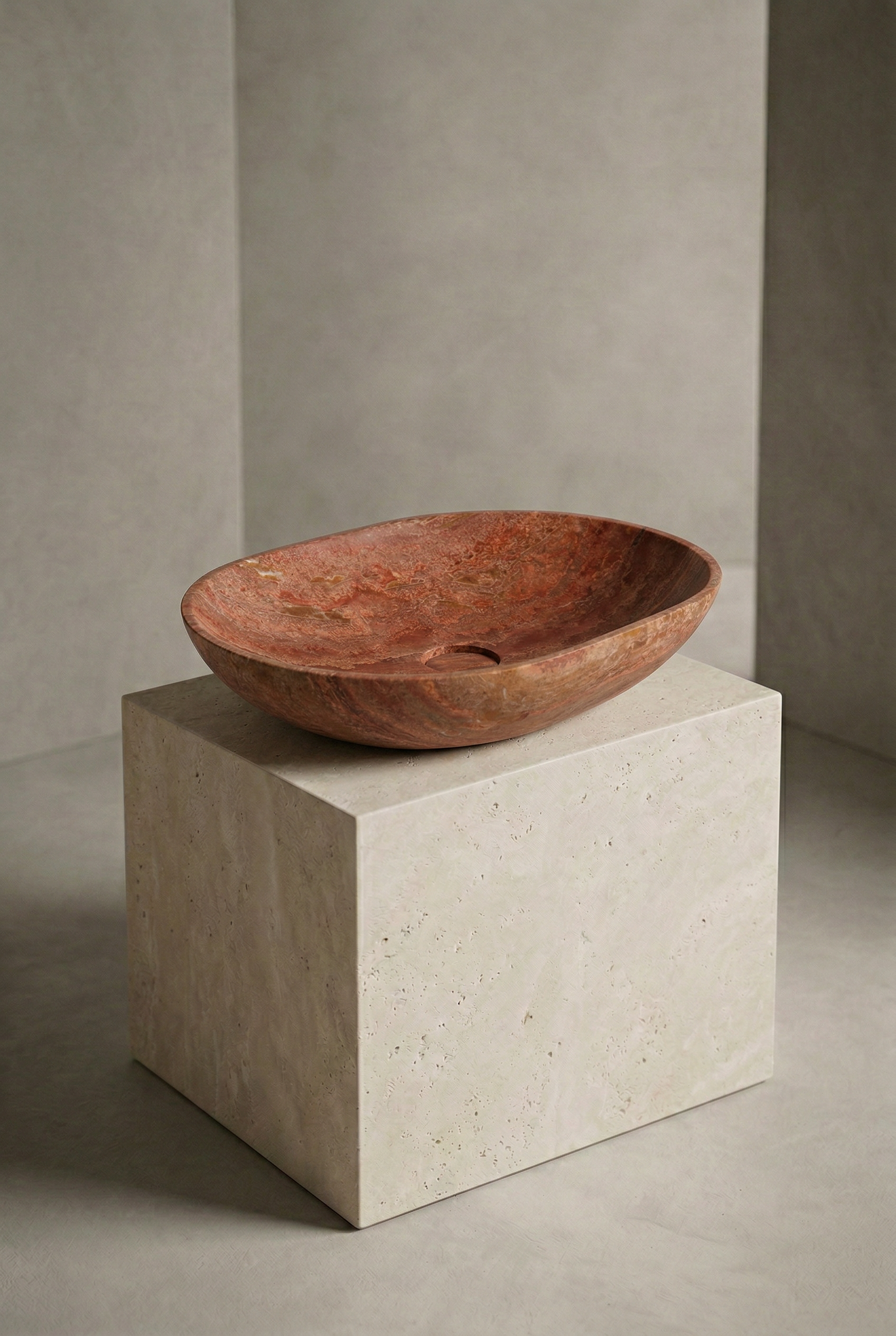 Red stone basin on a concrete pedestal against a neutral wall