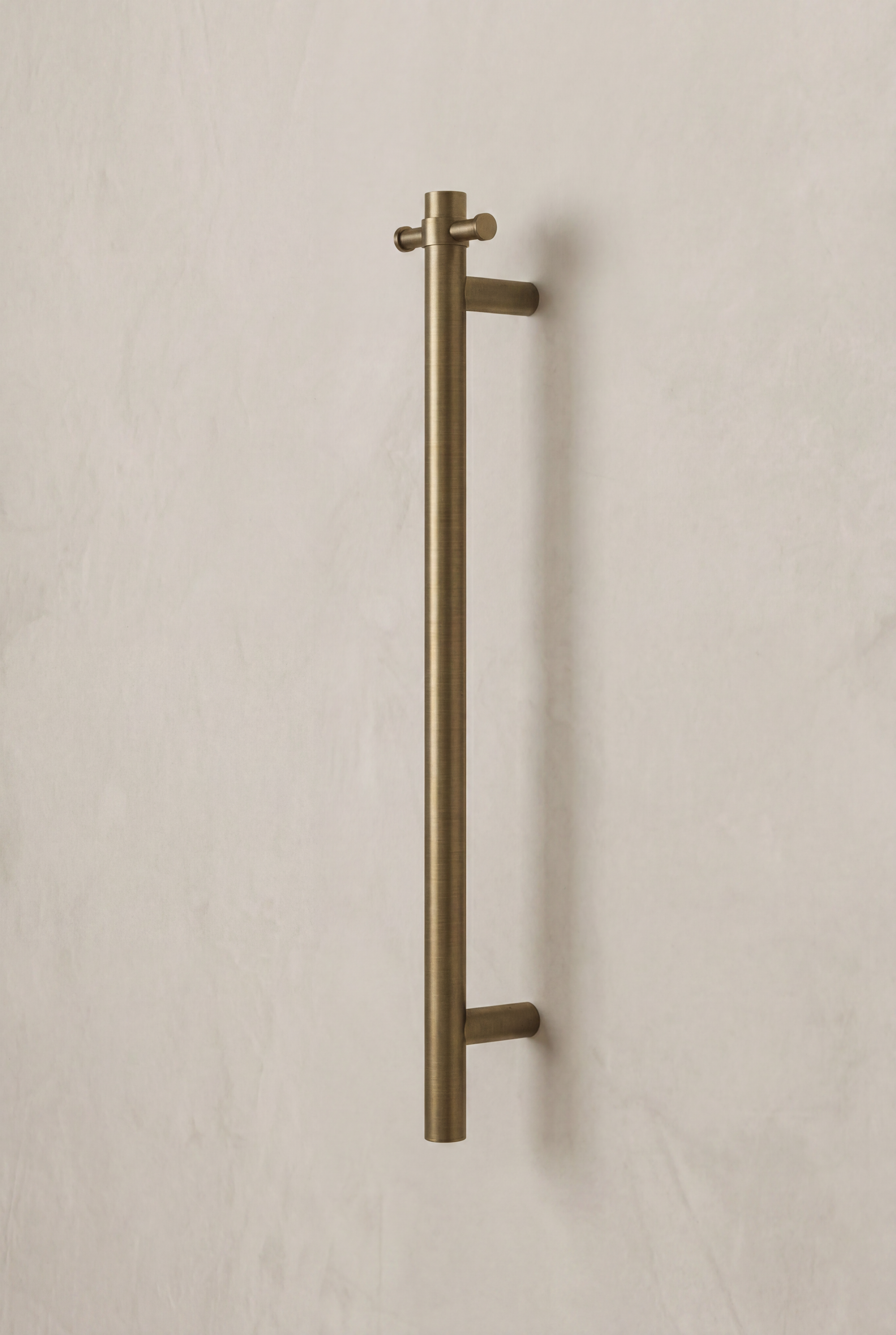 Antique Brass Heated Towel Rail on a beige wall