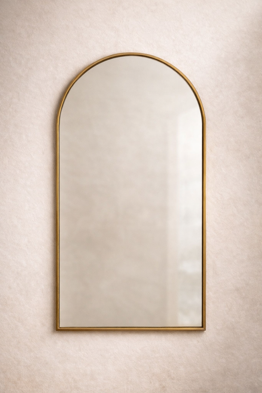 Arched mirror with gold frame on a beige wall