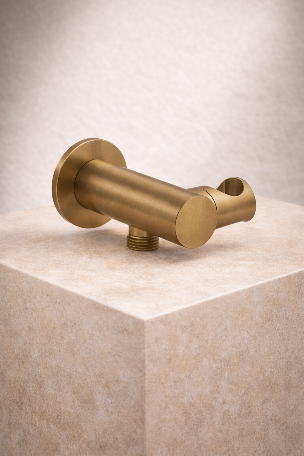 Antique Brass shower bracket on a beige cube with a neutral background