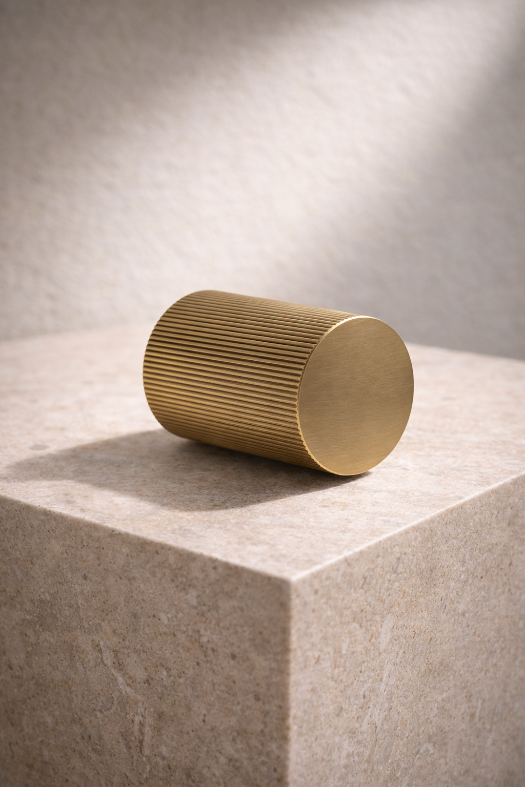 Gold cylindrical door knob object on a textured surface with soft lighting