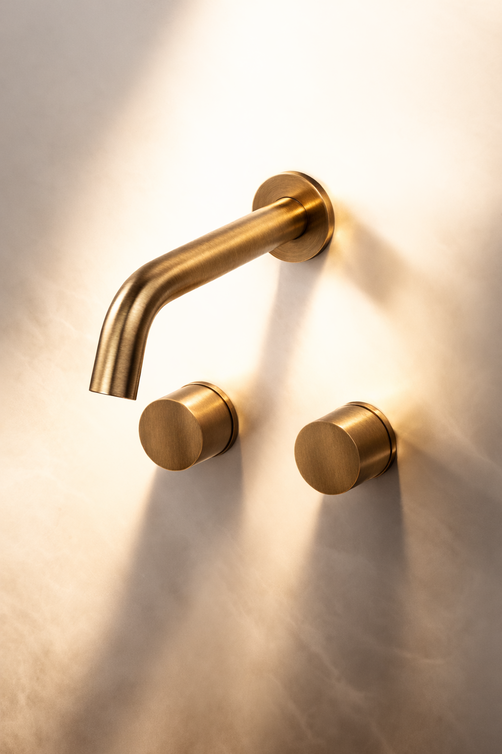 Gold wall-mounted faucet and handles on a light-colored wall
