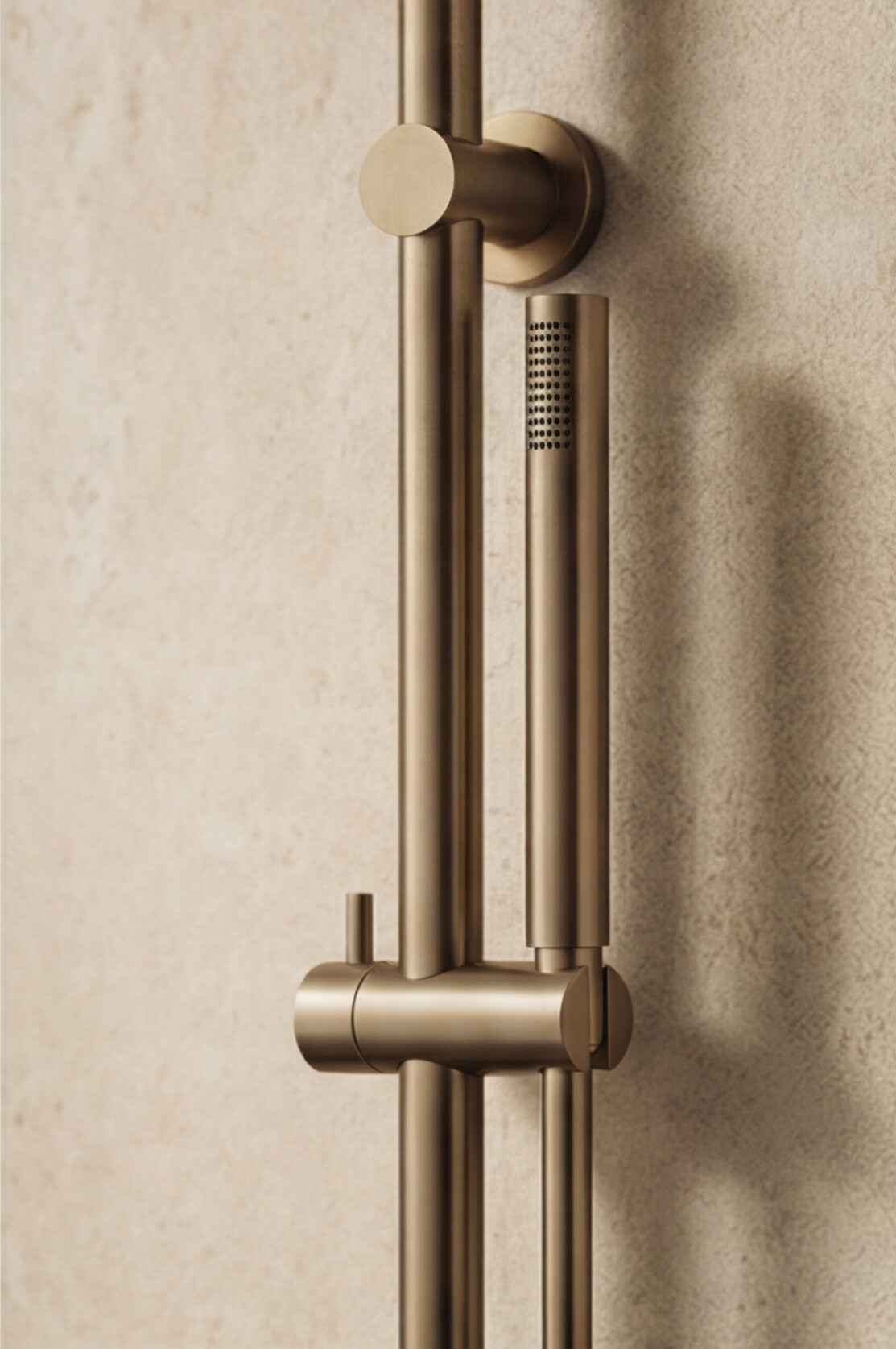 Antique Brass shower handle with handheld shower head on a beige wall