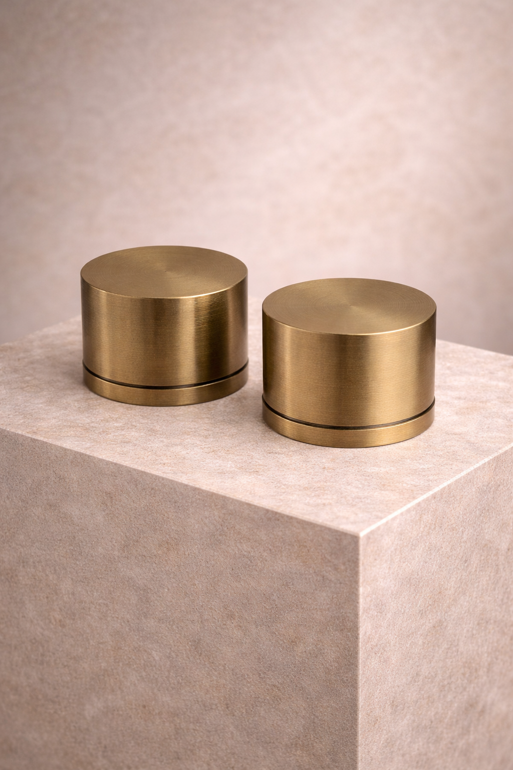 Two Antique brass cylindrical objects on a beige surface with a neutral background